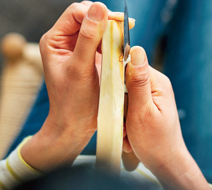 【7-1】材料は左手の親指と人差し指で支えて胸に押し当て、ナイフは人差し指から小指で柄を包むように持ち、親指を刃元の側面に押し付けます。切っ先を前へ傾け、刃元を材料に当てる。